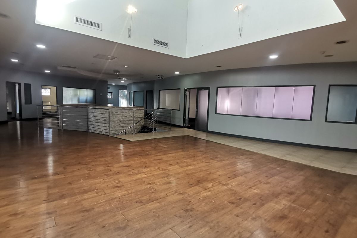 Spacious open-plan office area featuring a central reception desk, high ceilings with a large skylight, and modern stainless steel balustrades.