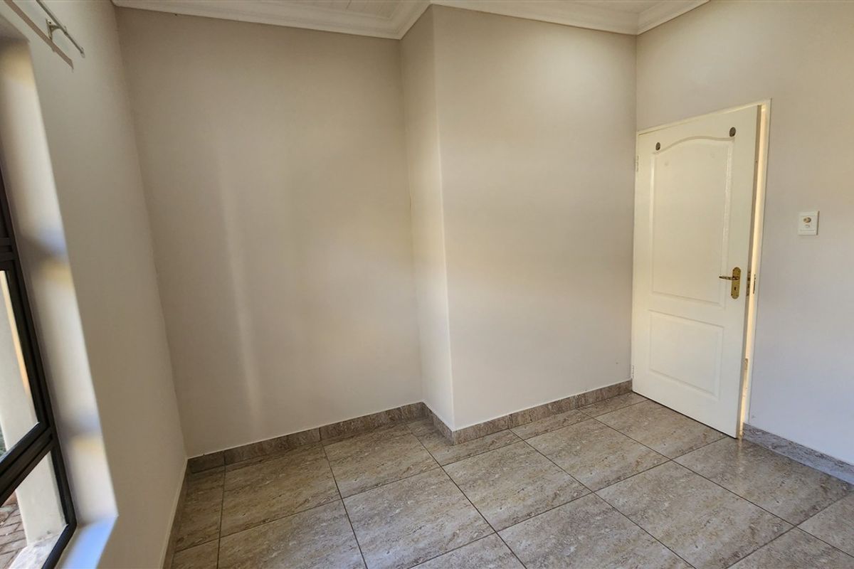 An empty bedroom featuring neutral wall paint, tiled flooring, and a standard internal door, offering a clean and versatile space.