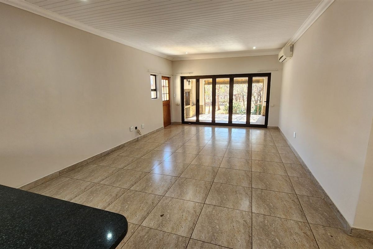 Spacious, light-filled living area featuring neutral tiled flooring, coved ceilings, and large sliding glass doors providing seamless access to the outdoor patio.