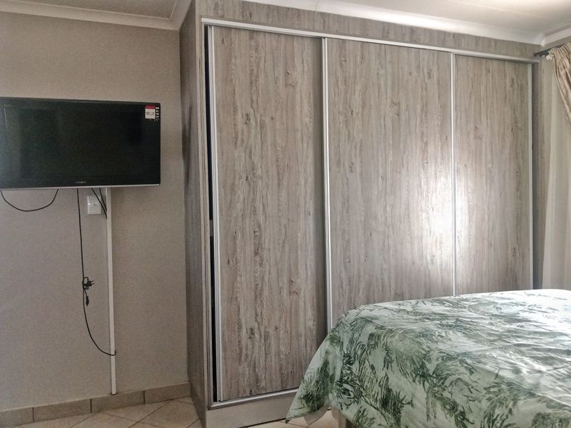 A bedroom featuring a large built-in wardrobe with wood-grain sliding doors, tiled flooring, and coved ceiling detailing.