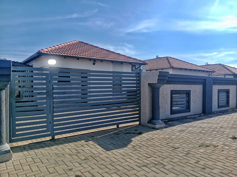 Front exterior view of a residential property featuring a tiled roof, secure boundary wall, and a modern sliding gate with a paved driveway.