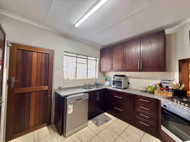 A functional kitchen featuring dark wood cabinetry, granite countertops, a built-in oven, and tiled flooring, providing a practical workspace with ample storage.