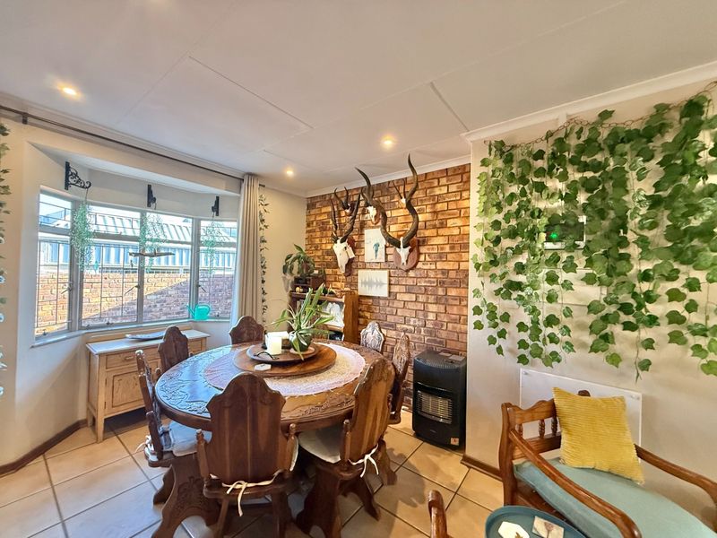 Dining room featuring an exposed brick wall, tiled flooring, and a bay window, providing a warm and characterful space for family meals.