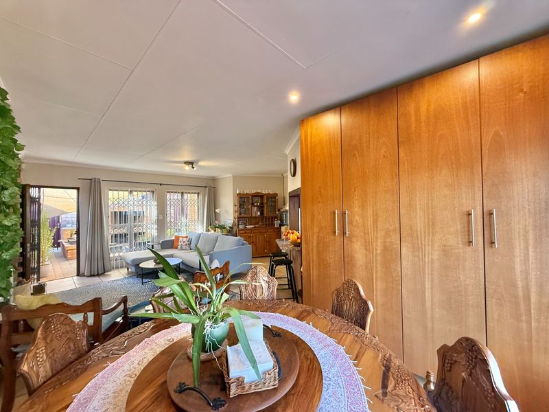 Spacious open-plan living and dining area featuring extensive built-in wooden cabinetry, tiled flooring, and large sliding doors leading to an outdoor patio.