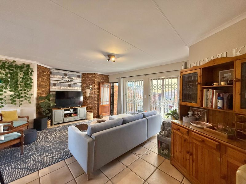 Spacious living room featuring an exposed brick wall, tiled flooring, and sliding glass doors providing access to the outdoor area.