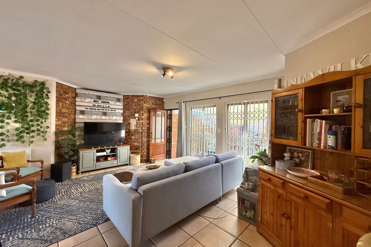 Spacious living room featuring an exposed brick wall, tiled flooring, and sliding glass doors providing access to the outdoor area.