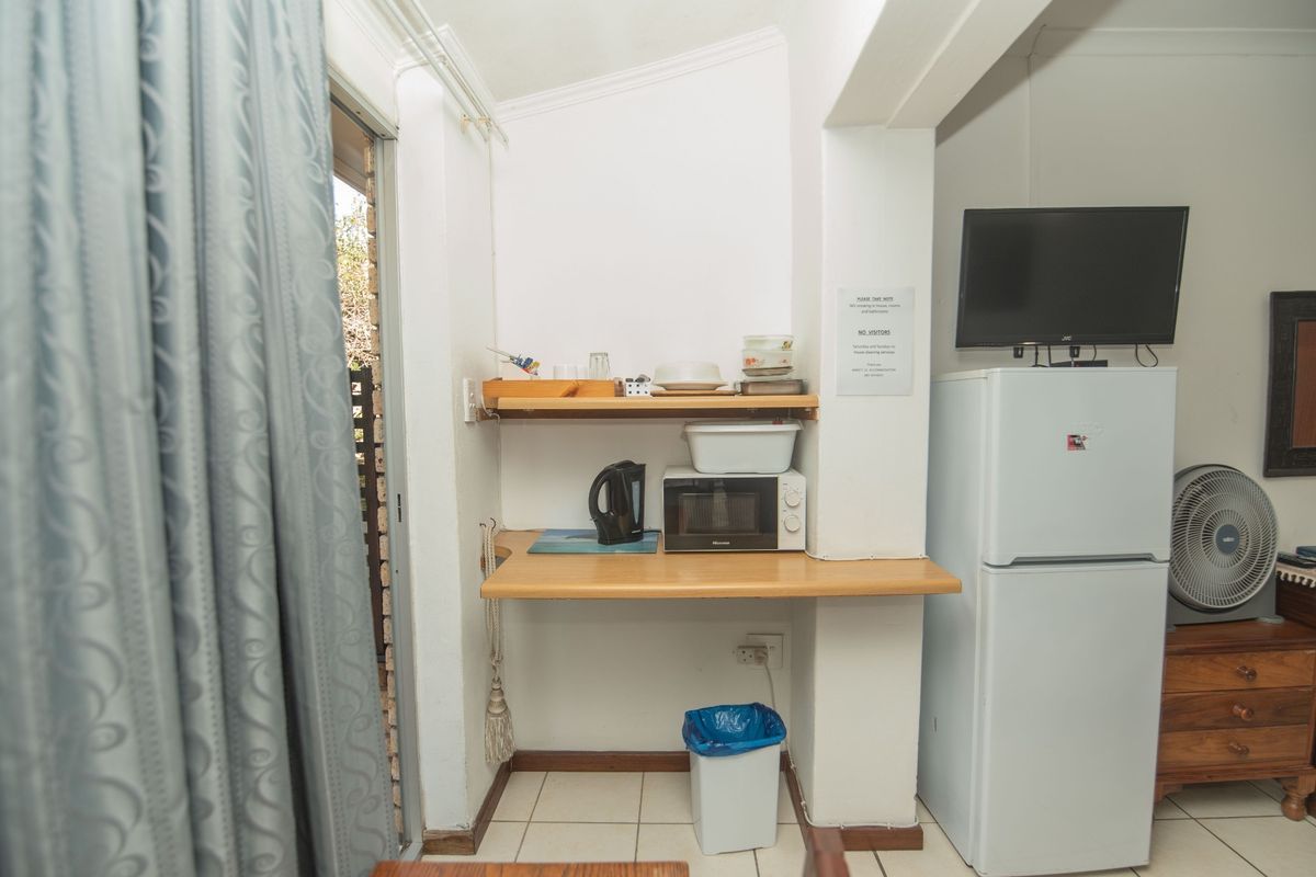 A compact kitchenette area featuring built-in shelving, a functional countertop, and tiled flooring, providing basic food preparation space.