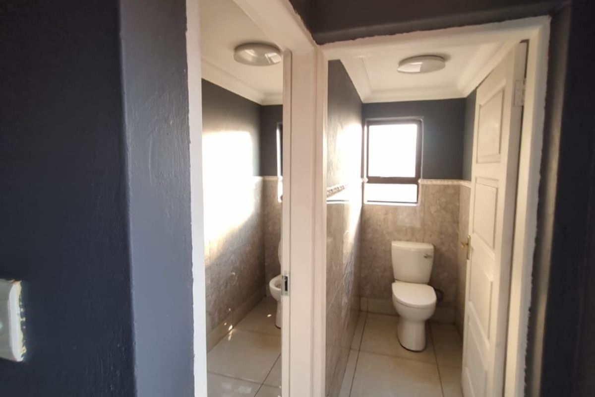 A clean, functional bathroom featuring tiled flooring, wall tiling, and a standard toilet, presented in a neutral, well-maintained condition.