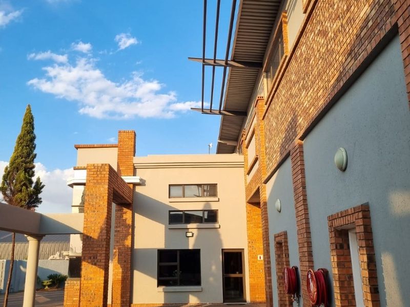 Exterior view of an industrial property featuring face brick detailing, paved driveway, and integrated fire safety equipment.