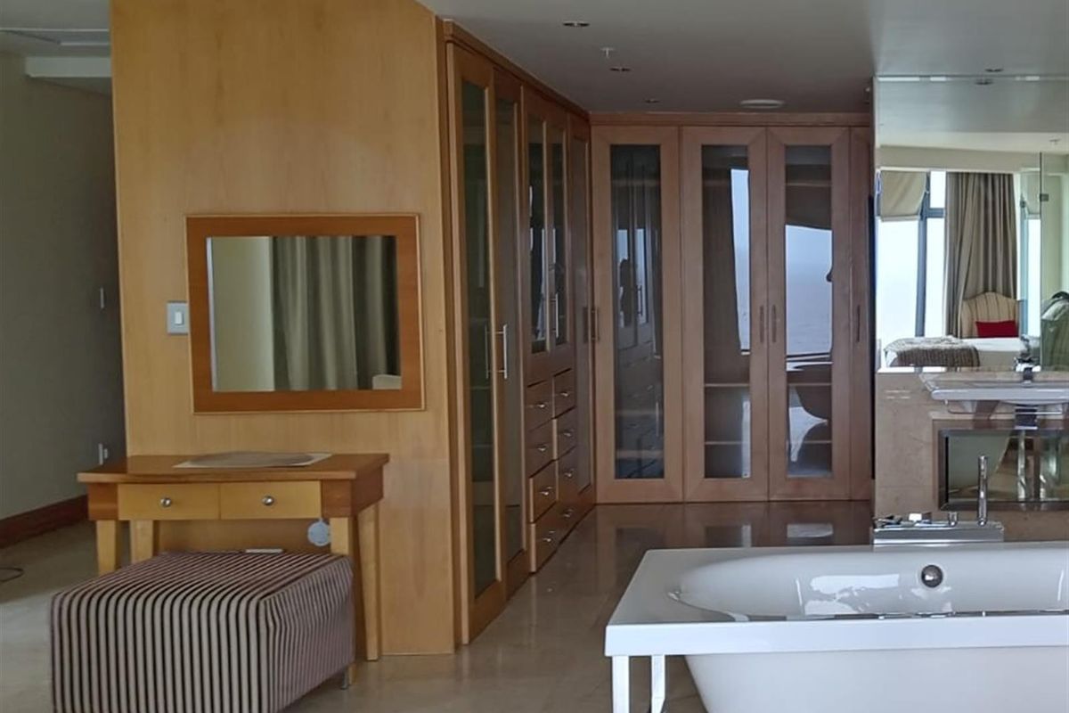 Spacious bathroom featuring extensive built-in wooden cabinetry, a modern freestanding bathtub, and tiled flooring with integrated vanity area.