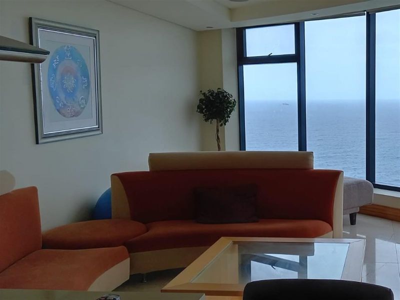 Spacious living area featuring large floor-to-ceiling windows with expansive ocean views and modern tiled flooring.