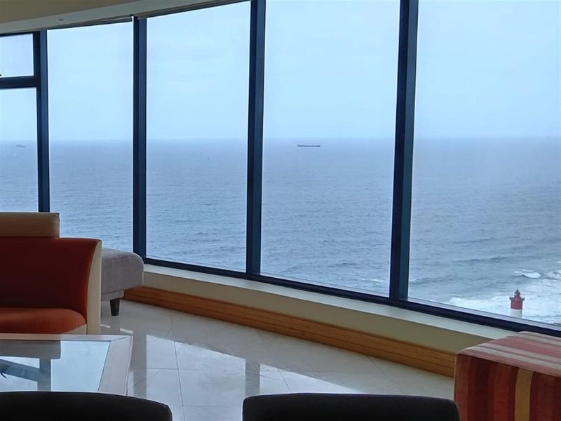 A bright living area featuring expansive floor-to-ceiling windows that offer panoramic ocean views and natural light.