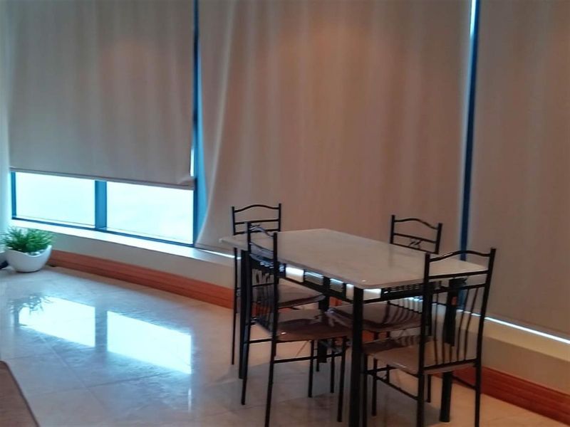 A bright dining area featuring large windows with roller blinds and polished tiled flooring, offering a clean and neutral space.