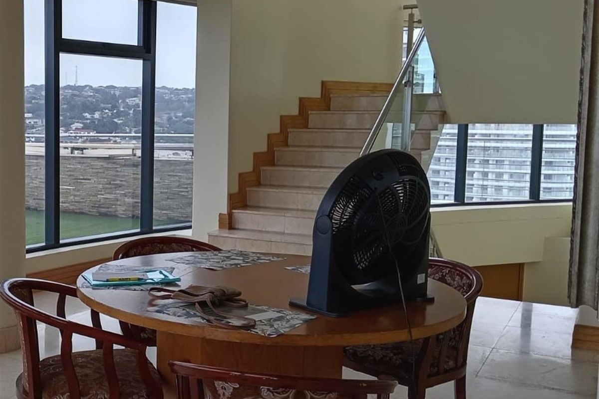 Spacious living area featuring a modern staircase with glass balustrade and expansive floor-to-ceiling windows offering natural light and views.