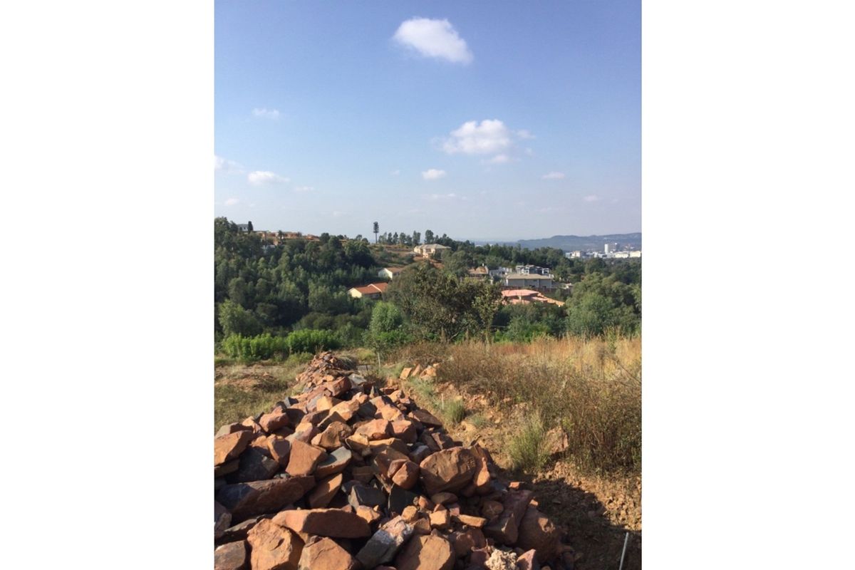 A scenic view overlooking a hilly landscape with residential properties and natural vegetation, showcasing the potential of the vacant land.