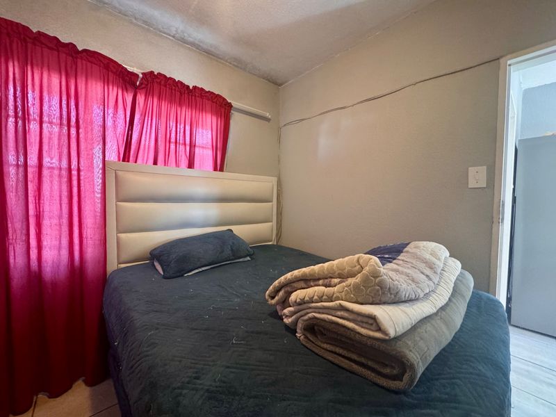 A bedroom featuring tiled flooring and visible ceiling wear, requiring cosmetic updates to improve the overall finish and presentation.