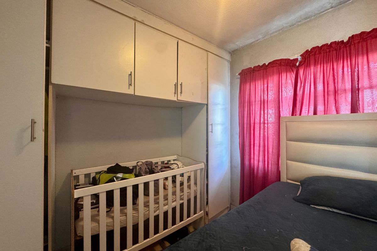 Bedroom featuring built-in cupboards and overhead storage cabinets, requiring some ceiling maintenance and cosmetic updates.