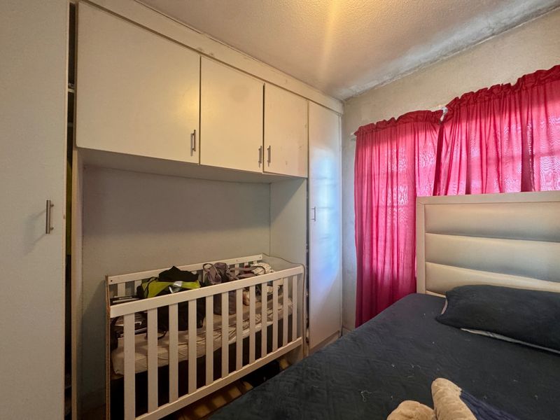 Bedroom featuring built-in cupboards and overhead storage cabinets, requiring some ceiling maintenance and cosmetic updates.