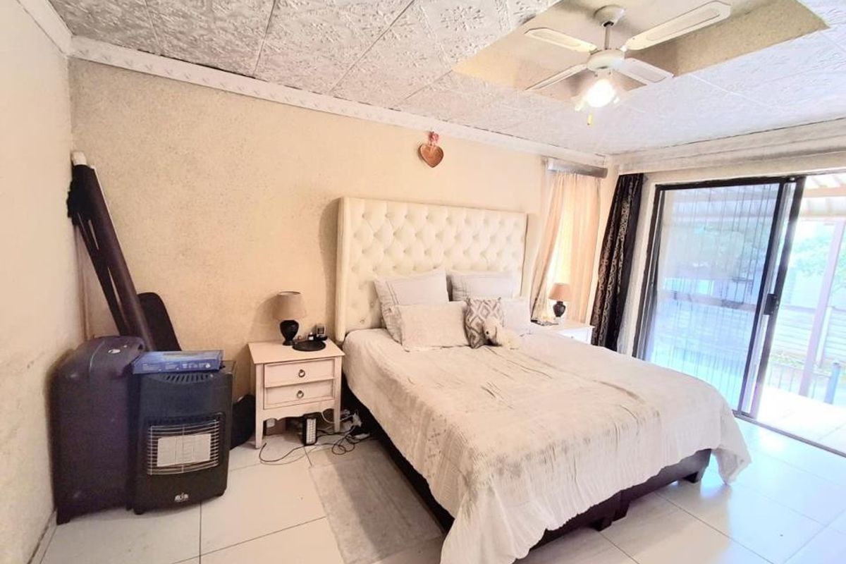 A bedroom featuring tiled flooring, a ceiling fan, and sliding glass doors providing access to the exterior.