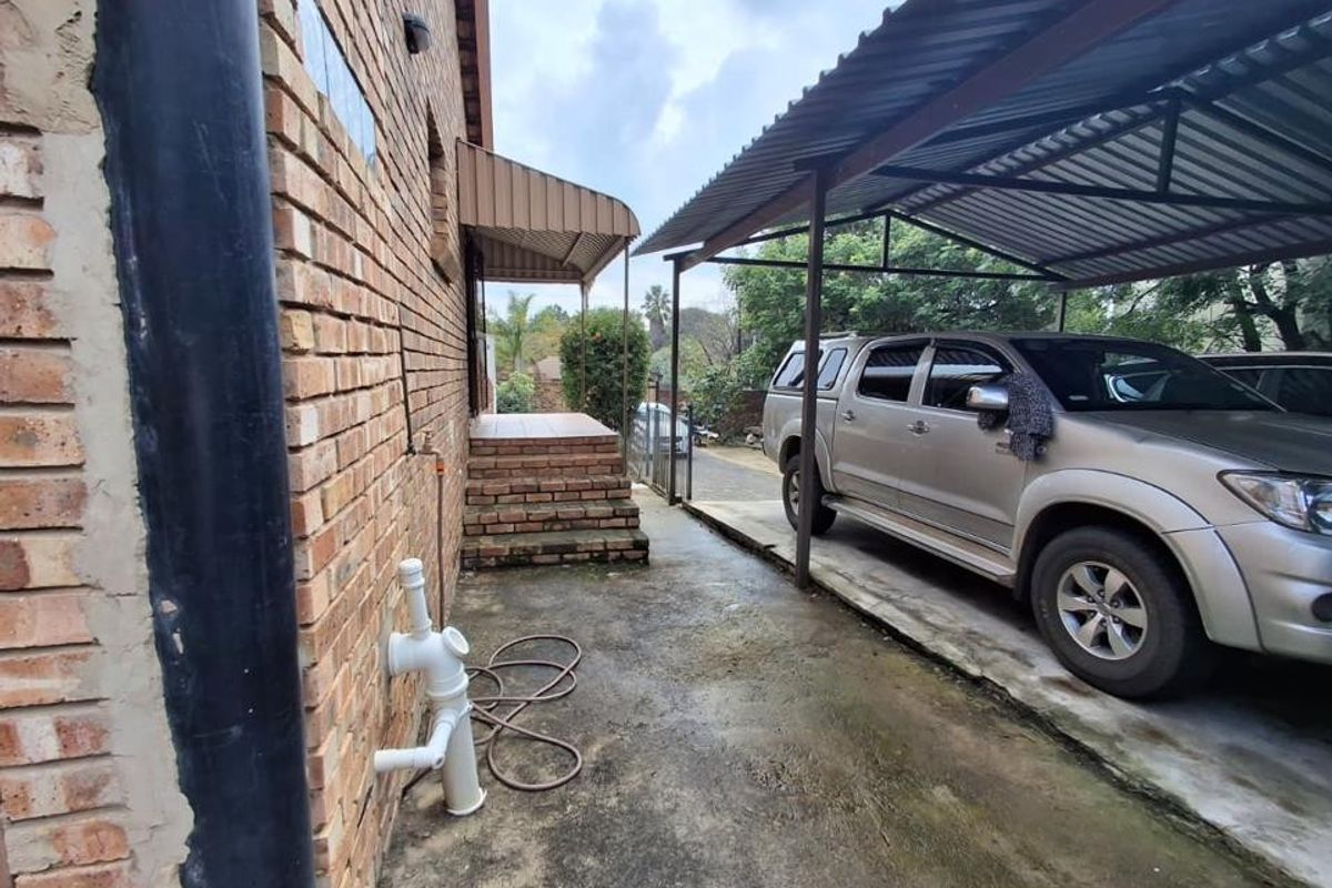 Side exterior area featuring a metal carport structure, brick facade, and concrete driveway with external plumbing fixtures.