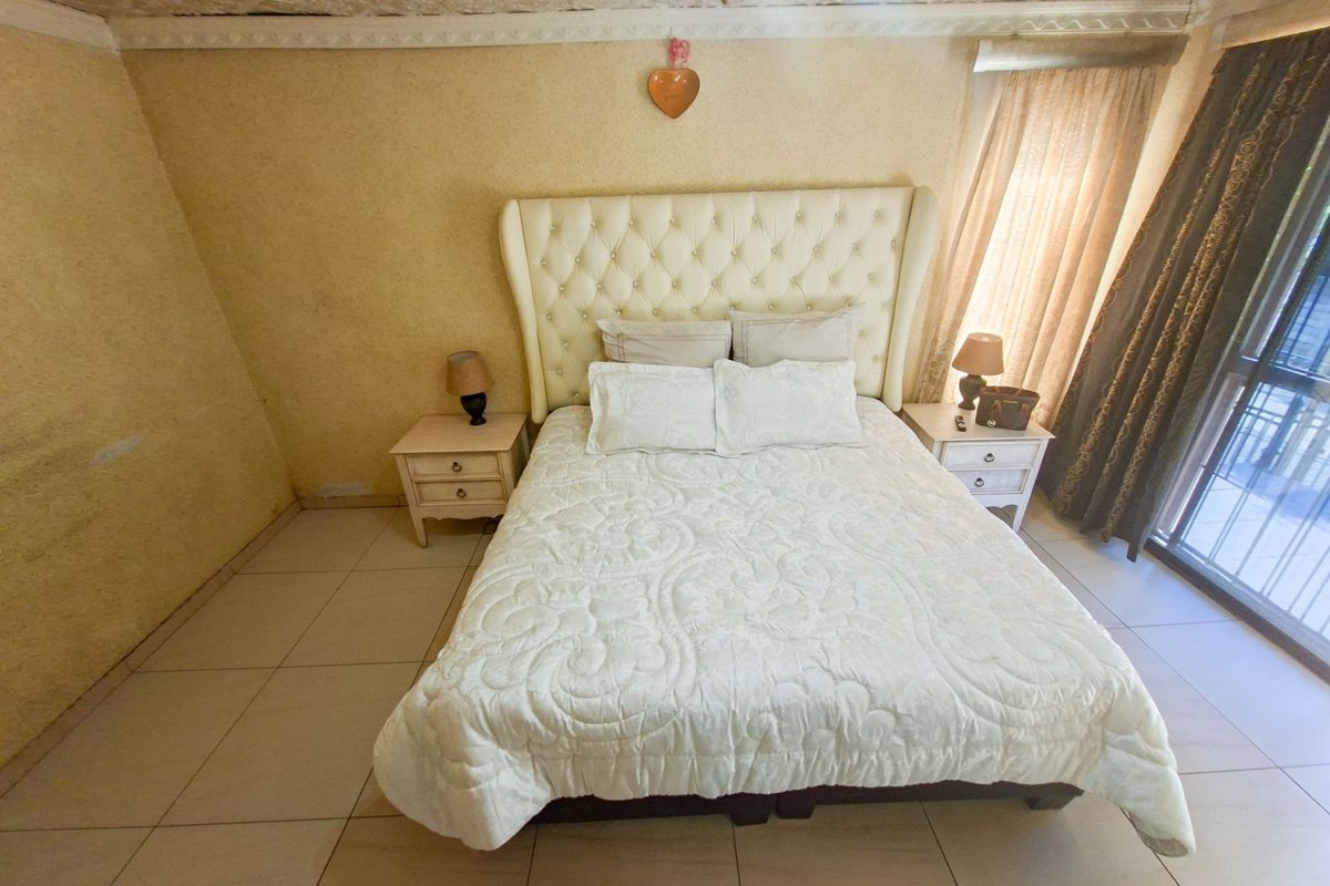 A bedroom featuring tiled flooring, a textured ceiling, and a sliding glass door providing access to the exterior.