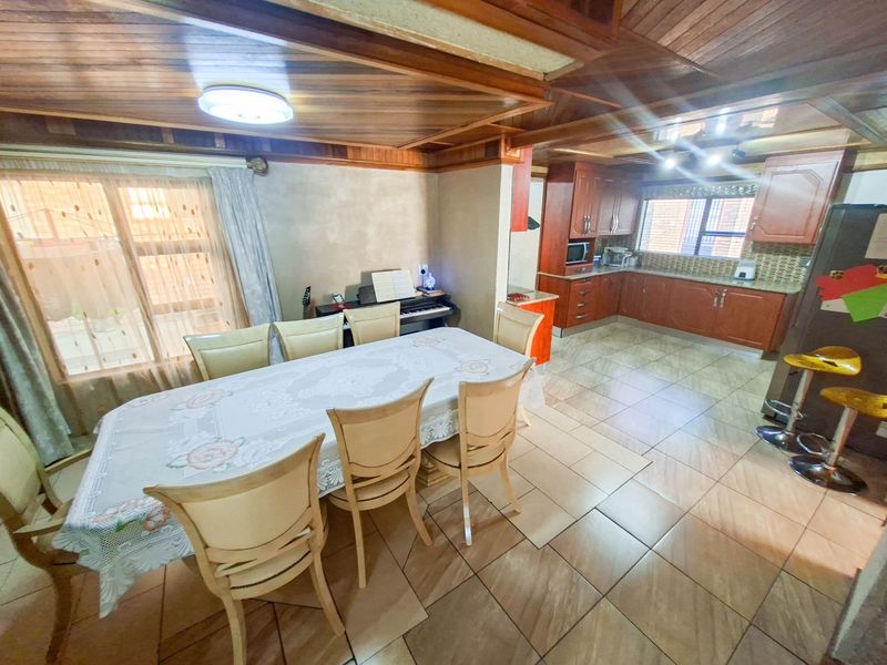 Open-plan kitchen and dining area featuring wooden ceilings, tiled floors, and traditional timber cabinetry with granite countertops.
