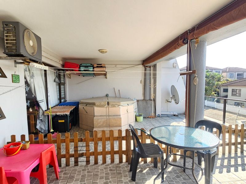 Spacious covered balcony featuring tiled flooring, a glass balustrade, and an integrated air conditioning unit, offering potential for an enhanced outdoor living area.