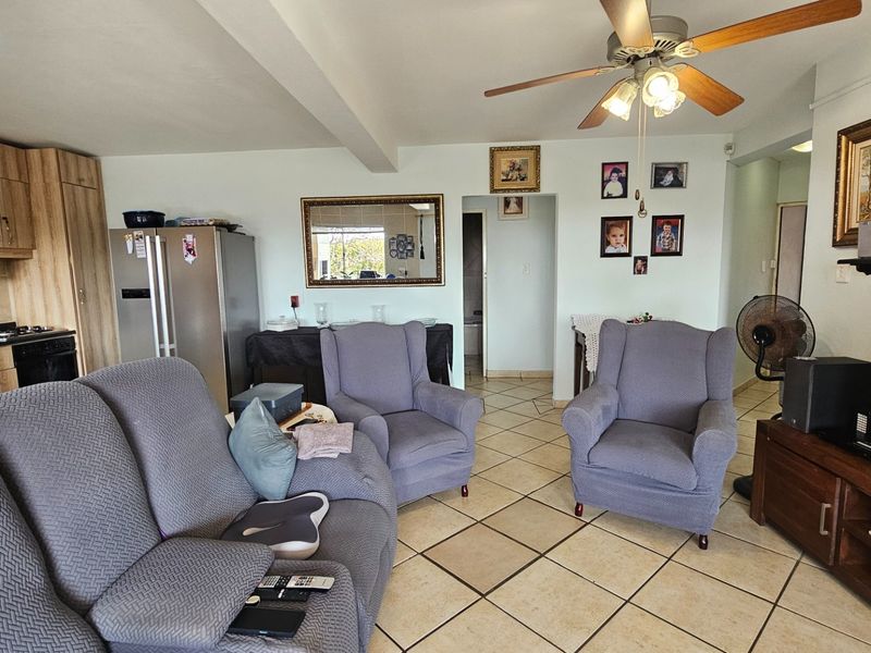 Open plan living and kitchen area featuring tiled flooring, built-in cabinetry, and a ceiling fan, providing a functional and connected living space.