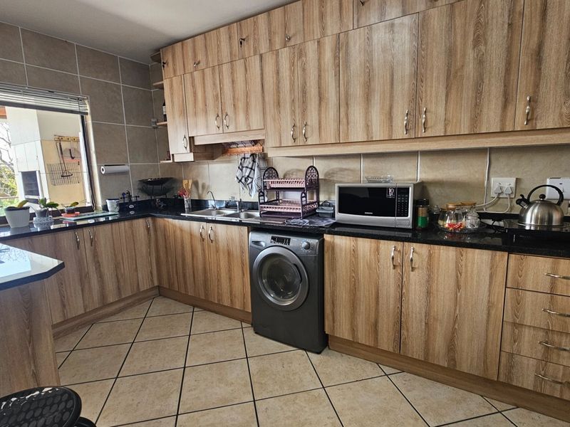 A functional kitchen featuring wood-grain cabinetry, granite countertops, tiled backsplash, and integrated appliances, offering a practical layout with ample storage space.
