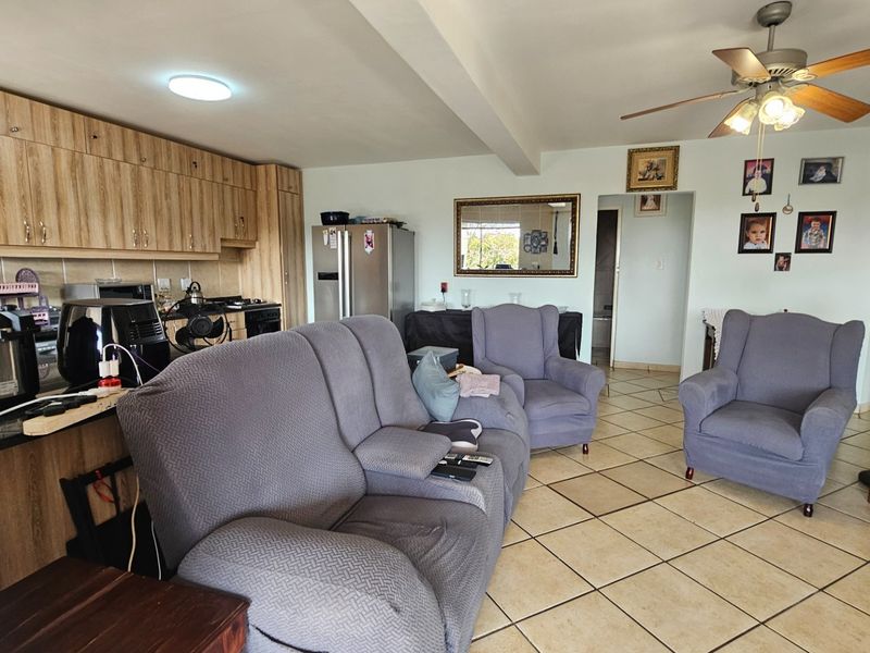 Open-plan living area featuring a kitchen with built-in cabinetry and tiled flooring, seamlessly connected to the lounge space.