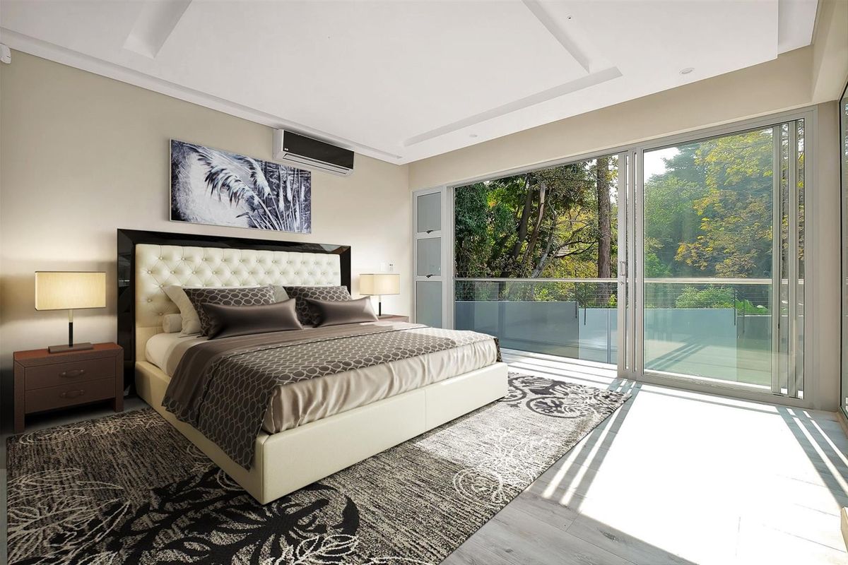 Spacious bedroom featuring modern recessed ceiling, air conditioning, and large sliding glass doors opening onto a balcony with scenic garden views.