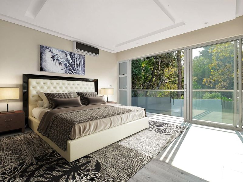 Spacious bedroom featuring modern recessed ceiling, air conditioning, and large sliding glass doors opening onto a balcony with scenic garden views.