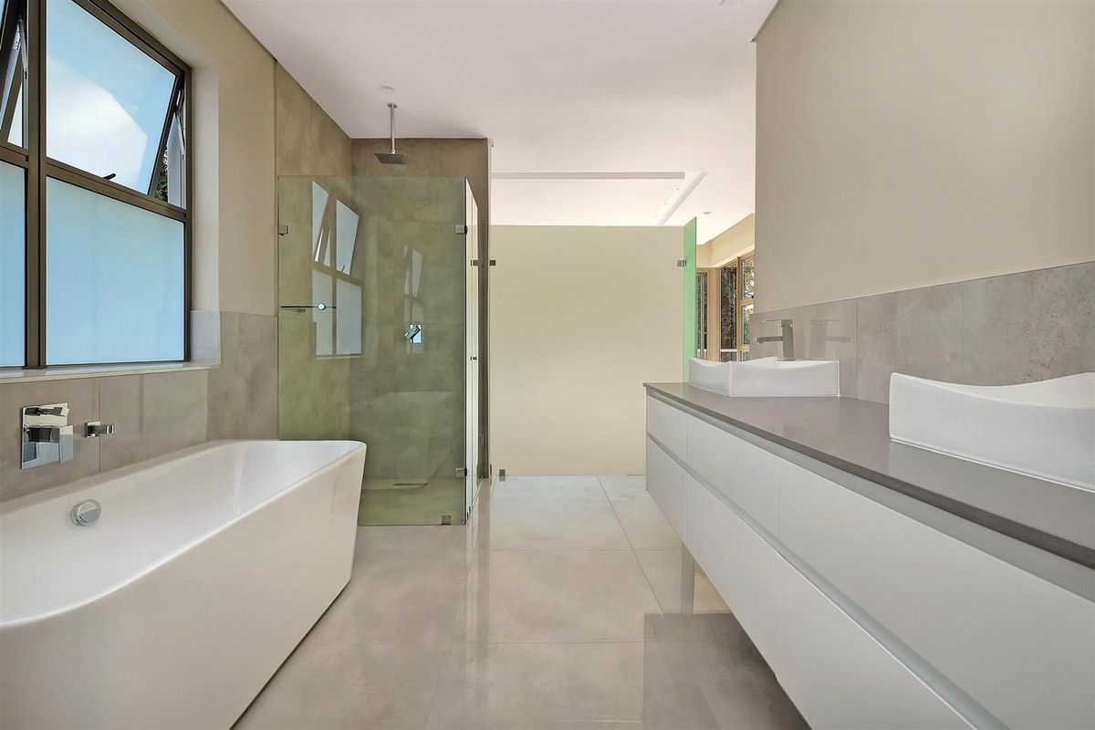 Modern bathroom featuring a sleek freestanding bathtub, glass-enclosed shower, and a double vanity with contemporary vessel sinks and high-quality finishes.