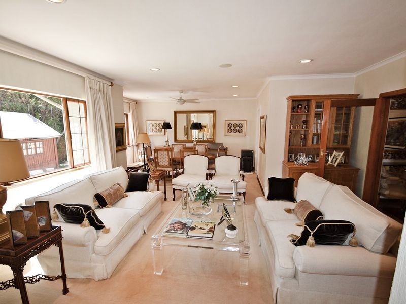 Spacious open-plan living and dining area featuring recessed lighting, a ceiling fan, and large windows providing natural light and garden views.