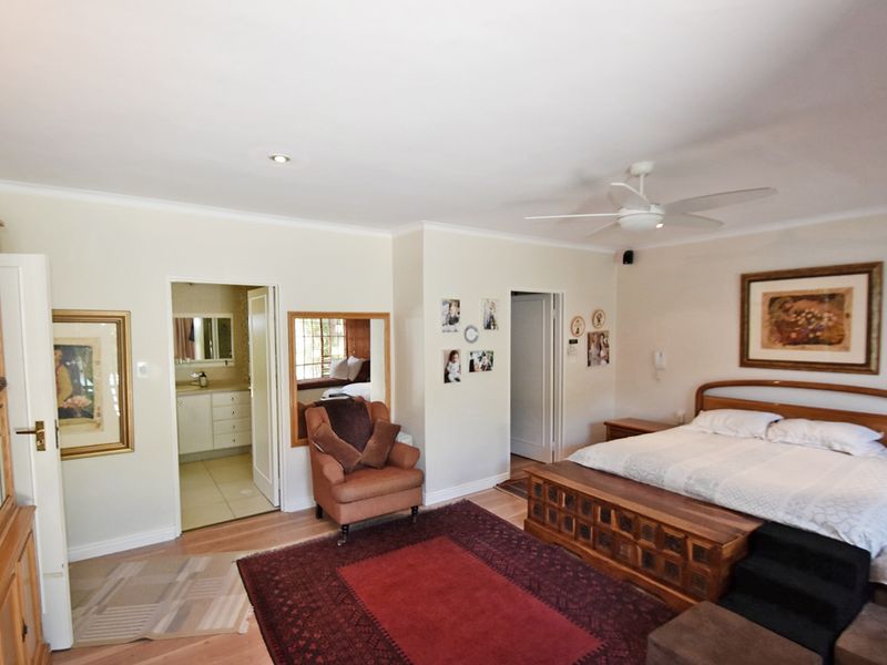 Spacious bedroom featuring hardwood flooring, a ceiling fan, recessed lighting, and direct access to an en-suite bathroom.