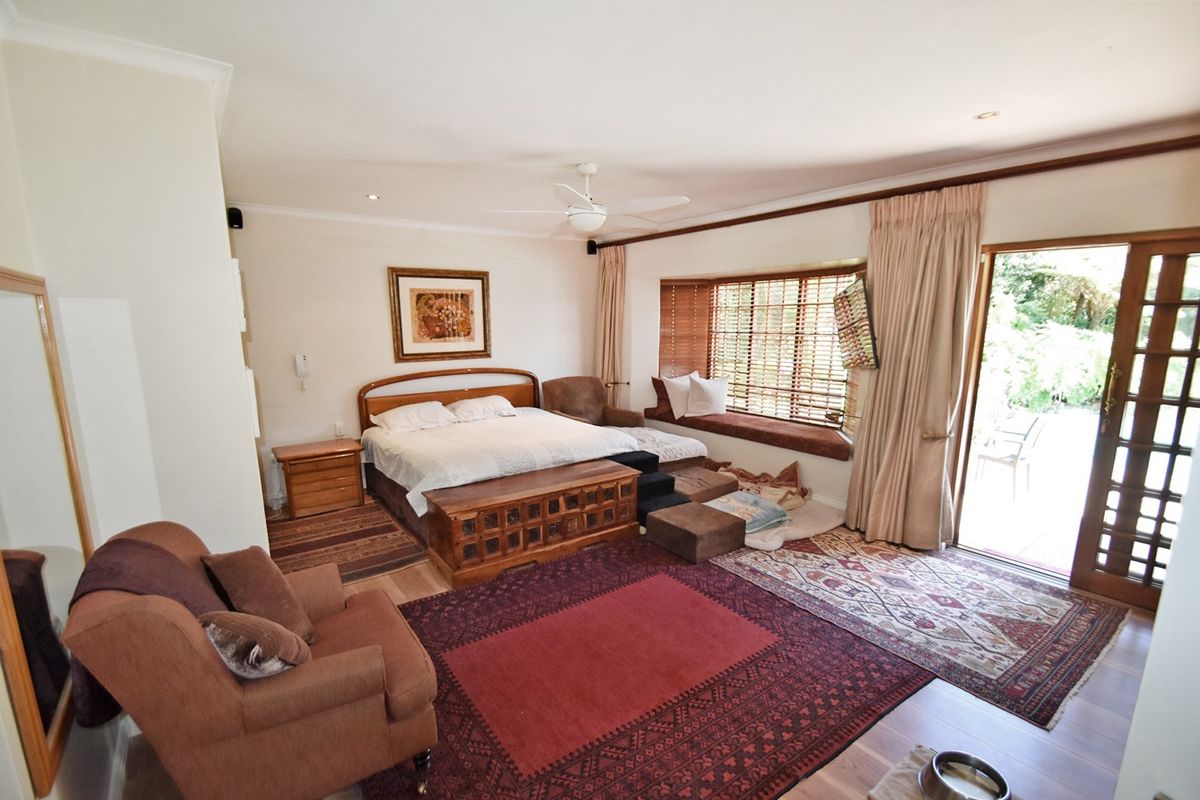 Spacious bedroom featuring a built-in bay window seat, ceiling fan, and direct access to the garden through sliding glass doors.