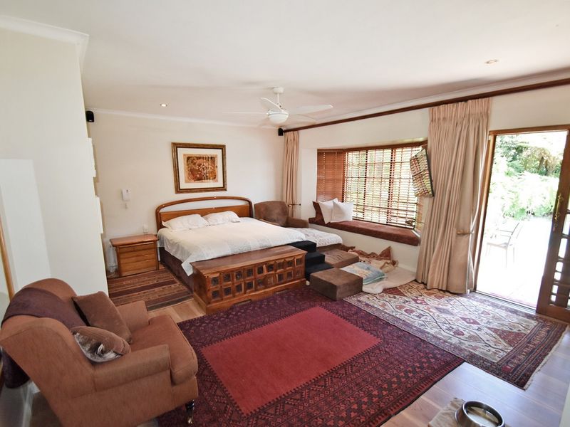 Spacious bedroom featuring a built-in bay window seat, ceiling fan, and direct access to the garden through sliding glass doors.