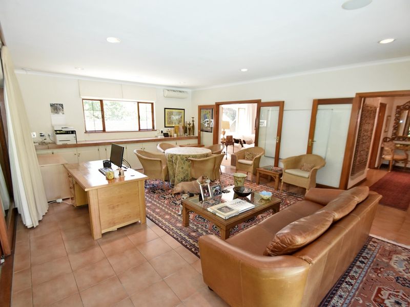 Spacious living area featuring tiled flooring, recessed lighting, built-in cabinetry, and multiple timber-framed glass doors providing access to adjacent rooms.