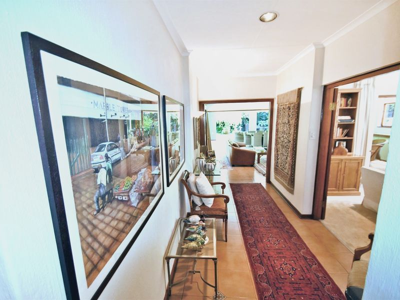 A well-maintained hallway featuring tiled flooring and recessed downlighting, providing a clear transition between the living areas and adjacent rooms.