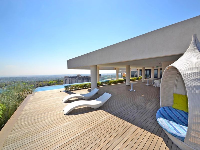Expansive outdoor terrace featuring timber decking, a modern infinity pool, and panoramic views, providing a luxurious space for relaxation and entertainment.