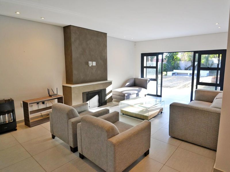 Spacious living room featuring a central fireplace, neutral tiled flooring, and large sliding glass doors providing direct access to the rear garden.