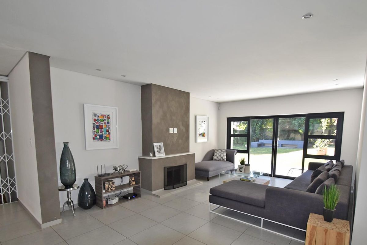 Spacious living room featuring a central fireplace, large sliding glass doors providing garden access, and neutral tiled flooring throughout.