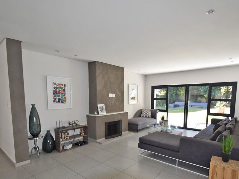 Spacious living room featuring a central fireplace, large sliding glass doors providing garden access, and neutral tiled flooring throughout.