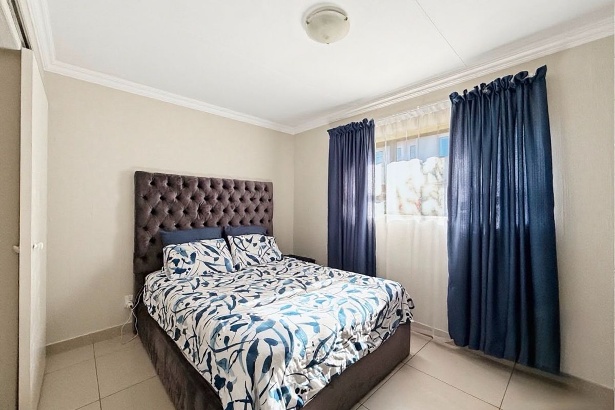 A well-maintained bedroom featuring neutral tiled flooring, built-in wardrobe storage, and classic ceiling cornice detailing.