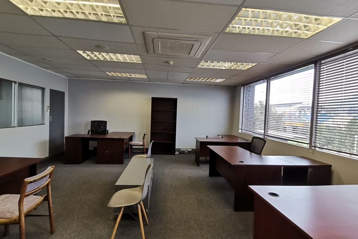 A functional office space featuring a suspended ceiling with recessed lighting, central air conditioning, and large windows with venetian blinds.