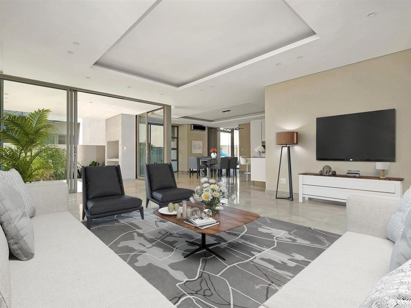 Spacious open-plan living area featuring modern tiled floors, recessed ceiling details, and large sliding glass doors that provide seamless access to the outdoor patio.