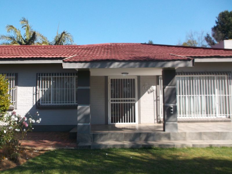 Front elevation of a single-story house featuring a tiled roof, covered porch entrance, and security bars on the windows.