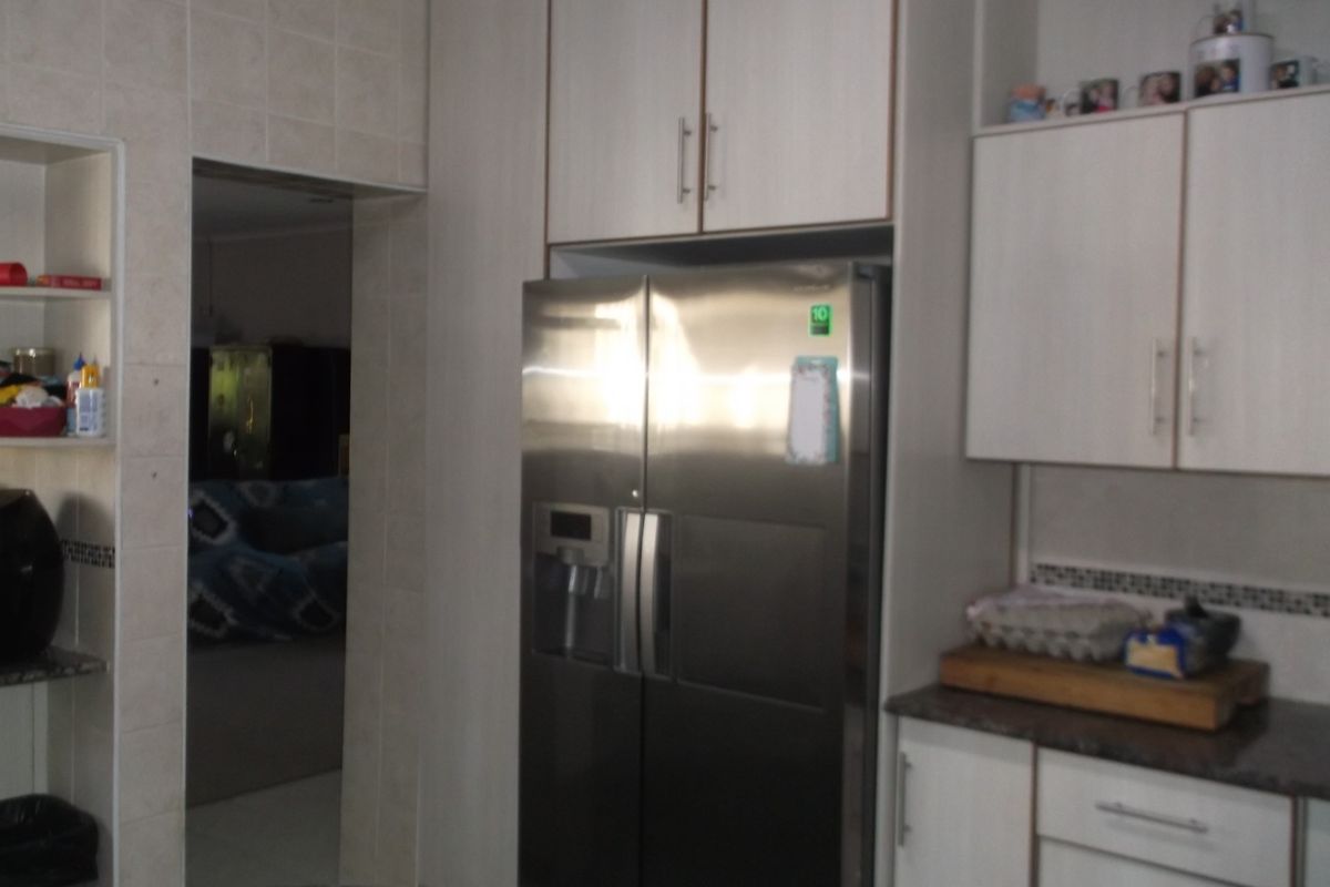 A functional kitchen area featuring built-in cabinetry, laminate countertops, and a tiled backsplash, providing ample storage and workspace.
