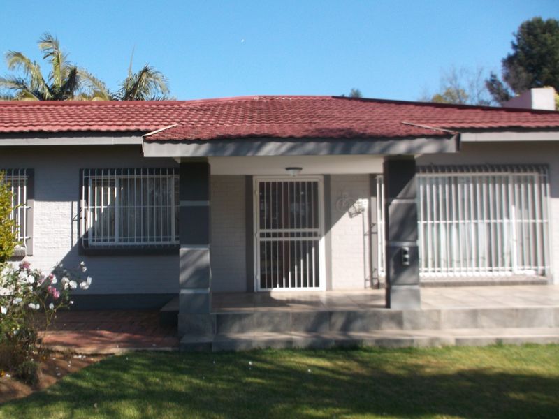 Front elevation of a single-story house featuring a tiled roof, covered entrance porch, and security bars on the windows.