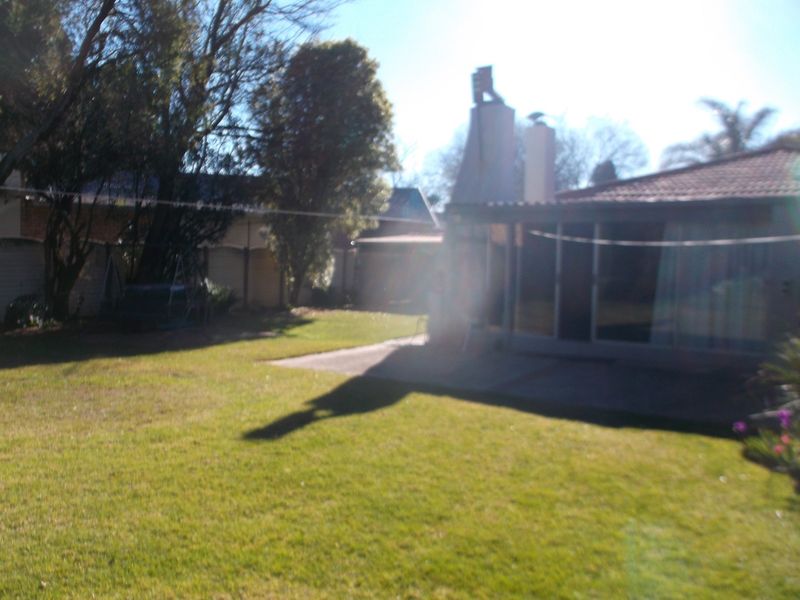 Rear view of the property featuring a lawn, concrete patio, and sliding glass doors leading into the home.